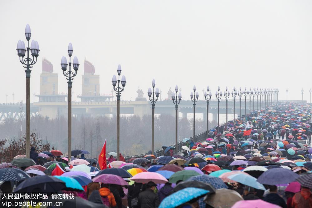 La gente en Nanjing desafía a la lluvia cruzando el recién renovado puente sobre el río Yangtse