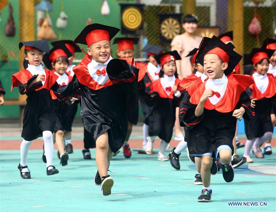 El 17 de junio de 2016, los niños de una guardería visten togas de graduación por el patio del centro en el distrito Hedong en Tianjin, China. [Foto / Xinhua]