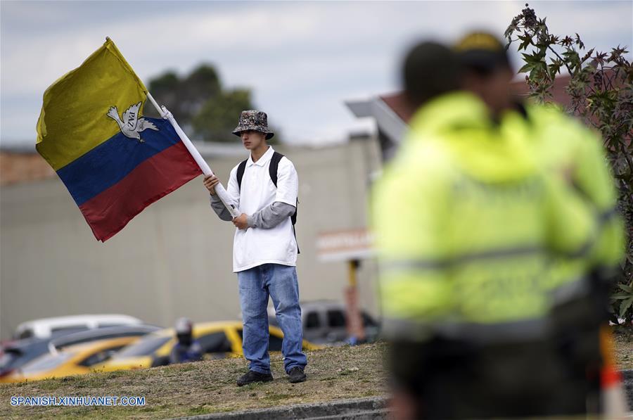 BOGOTA, enero 17, 2019 (Xinhua) -- Un residente ondea una bandera nacional colombiana frente a policías cerca del lugar donde se registró una explosión en el estacionamiento de la Escuela de Cadetes de Policía General Santander, en el sur de Bogotá, capital de Colombia, el 17 de enero de 2019. Aumentó a ocho el número de muertos y a más de 40 el de los heridos tras la detonación de un coche bomba en la Escuela de Cadetes de Policía General Santander, en la zona sur de Bogotá, Colombia, registrada el jueves. El alcalde de la capital colombiana, Enrique Peñalosa, reportó que desconocidos ingresaron un coche bomba al sitio y que la onda explosiva destruyó varias fachadas. (Xinhua/Jhon Paz)