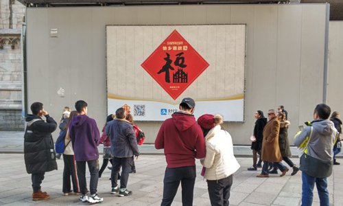 Los turistas chinos se reunieron alrededor de un cartel de la campaña de Alipay en las afueras de la Catedral de Milán durante las vacaciones del Año Nuevo Lunar de 2019.