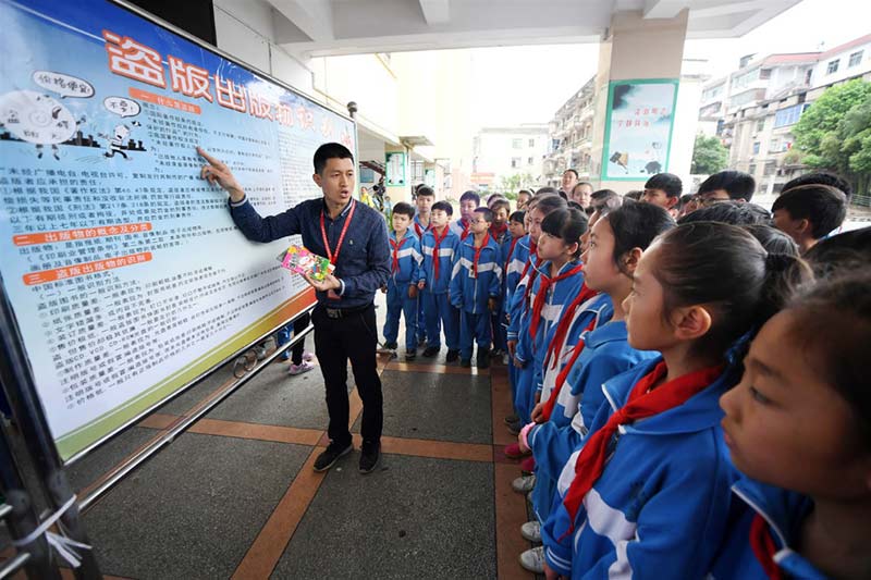 El 23 de abril de 2018, oficiales de la ley de la nueva oficina de Wenguang del condado Fenyi, ciudad de Xinyu en la provincia de Jiangxi, explicaron los métodos de identificación de protección de propiedad intelectual y publicaciones pirateadas a estudiantes en una escuela primaria del condado Fenyi. (Zhou Liang / Pueblo en Línea)