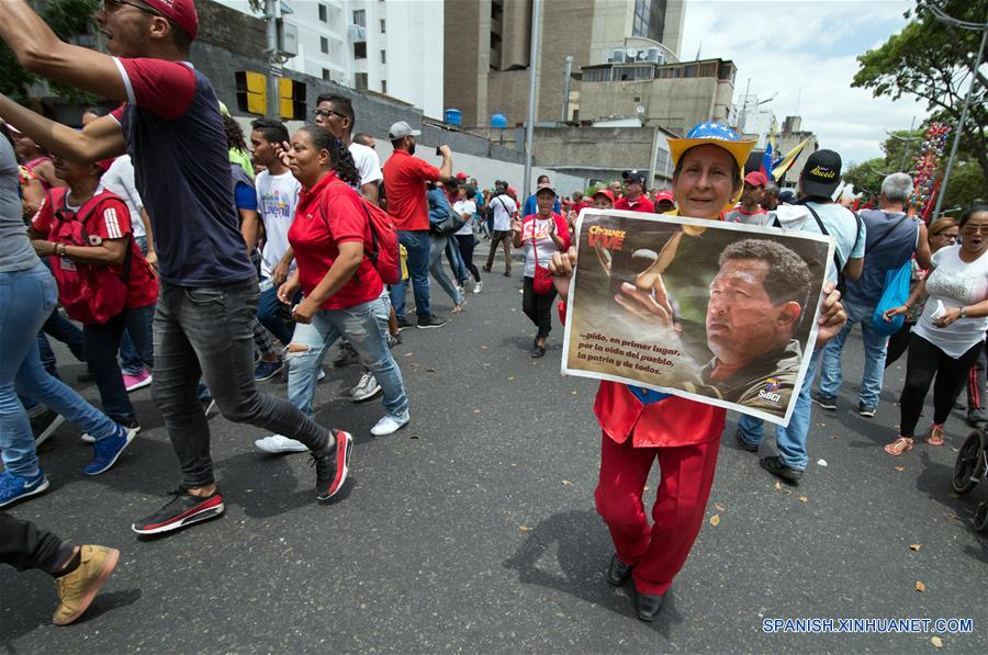 Una mujer sostiene una imagen del fallecido presidente venezolano, Hugo Chávez, durante una marcha en apoyo al presidente de Venezuela, Nicolás Maduro, en Caracas, Venezuela, el 23 de marzo de 2019. El presidente venezolano, Nicolás Maduro, anunció el sábado durante un acto en Caracas la captura de un "poderoso jefe paramilitar colombiano" en el estado de Carabobo (centro-norte). (Xinhua/Marcos Salgado)