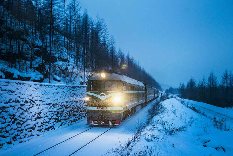 Un tren circula por la nieve en el área de las montañas del Gran Khingan, en la provincia de Heilongjiang del noreste de China, en enero de 2016. [Foto de Wang Tiancheng / para chinadaily.com.cn]