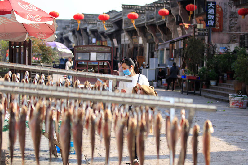 Una mujer mira el pescado seco en un puesto callejero en Datong, una antigua ciudad en la orilla oriental del río Yangtze en Tongling, provincia de Anhui, el 25 de marzo de 2019. [Foto de Zhu Lixin / chinadaily.com.cn]