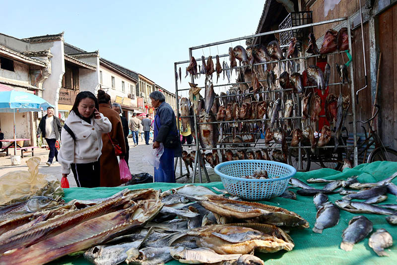 Una visitante compra pescado seco en un puesto callejero en Datong, una antigua ciudad en la orilla oriental del río Yangtze en Tongling, provincia de Anhui, el 25 de marzo de 2019. [Foto de Zhu Lixin / chinadaily.com.cn]