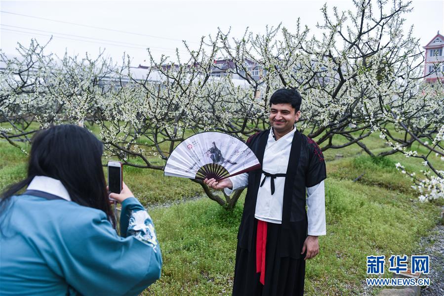 El 31 de marzo, un visitante extranjero, vestido con trajes Hanfu, se hace fotos en los campos llenos de flores.