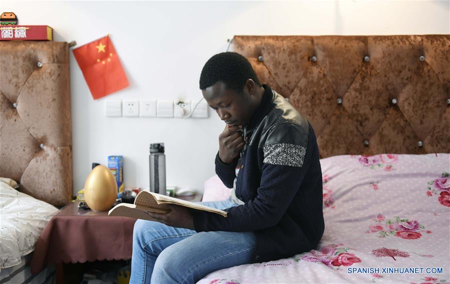  HUNAN, 15 abril, 2019 (Xinhua) -- Imagen del 19 de marzo de 2019, de Mangeh III Fondzenyuy Cedric leyendo un libro en su cuarto, en la Universidad Agrícola de Hunan, en Changsha, provincia de Hunan, en el centro de China. Cedric, de 25 años, es de Camerún. Habiendo siendo testigo de la avanzada ciencia agrícola y tecnología y equipo de las empresas chinas, llegó a China en 2017 y estudió un posgrado con especialización en ingeniería de mecanización agrícola en la Escuela de Ingeniería de la Universidad de Hunan después de completar sus estudios de licenciatura. Cedric estudia principalmente mecanización y automatización agrícola, biología moderna, operación y gestión agrícola moderna, extensión de tecnología y ciencia agrícola y otros cursos profesionales en la universidad. Después de estudiar en China durante dos años, Cedric no sólo habla chino con fluidez, sino que también aprendió a operar más de 20 tipos de recursos agrícolas, dominó los métodos de manejo de información agrícola y se está convirtiendo en un talento agrícola moderno interdisciplinario. Cedric dijo que después de regresar a Camerún, aplicará lo que aprendió en China a la producción agrícola de su ciudad natal. Como Cedric, cada vez más estudiantes africanos van a Hunan a estudiar en los últimos años, especializándose en agronomía, medicina, administración de empresas, ingeniería civil, etc. Mientras aprendían conocimientos profesionales, sintieron el encanto de la cultura china y profundizaron la amistad con profesores y estudiantes de China. (Xinhua/Li Ga)