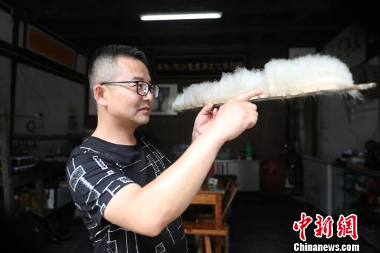 Jiang Guangming， un cocinero de este tipo de tofu, mide la longitud de los filamentos para determinar si el tofu ha fermentado completamente.[Foto: Fan Chengzhu/ Chinanews.com]