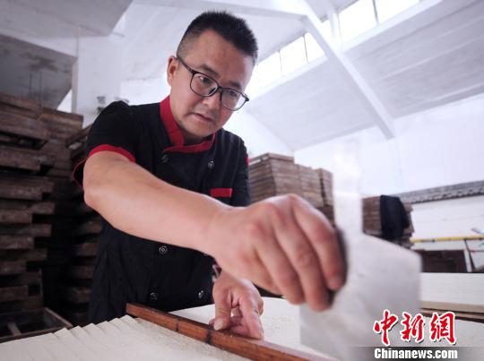 Jiang Guangming corta el entero tofu en tiras.[foto: Fan Chengzhu de Chinanews.com]