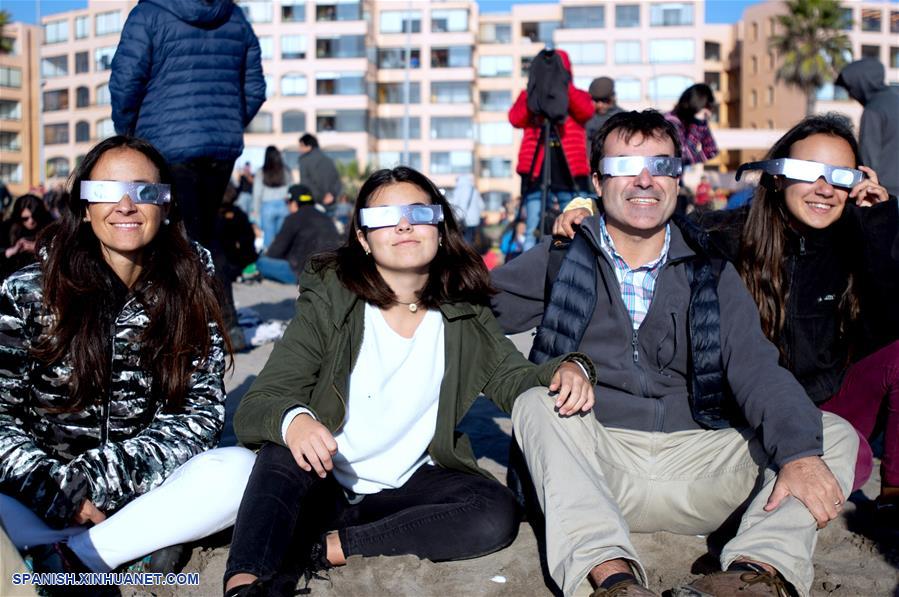 Personas utilizan lentes para observar el eclipse solar total, en la ciudad de La Serena, en la región de Coquimbo, Chile, el 2 de julio de 2019. Miles de personas se aglutinaron en las playas de La Serena y Coquimbo, unos 470 kilómetros al norte de Santiago y a nivel del mar, donde el punto central del eclipse solar total tuvo una duración de dos minutos y 15 segundos. (Xinhua/Jorge Villegas)