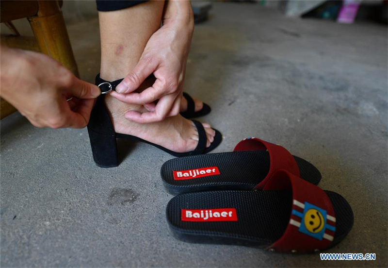 Liu Lihong se quita los zapatos de tacón para acometer las tareas domésticas.Dabaidi, Ruijin, provincia de Jiangxi, 19 de agosto del 2019.(Foto: Xinhua / Hu Chenhuan)
