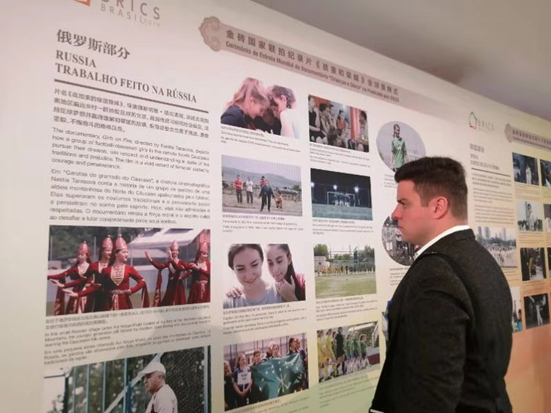 Un visitante lee el panel de la película producida por los BRICS "Niños y Gloria". Por Liu Xuxia, Diario del Pueblo.