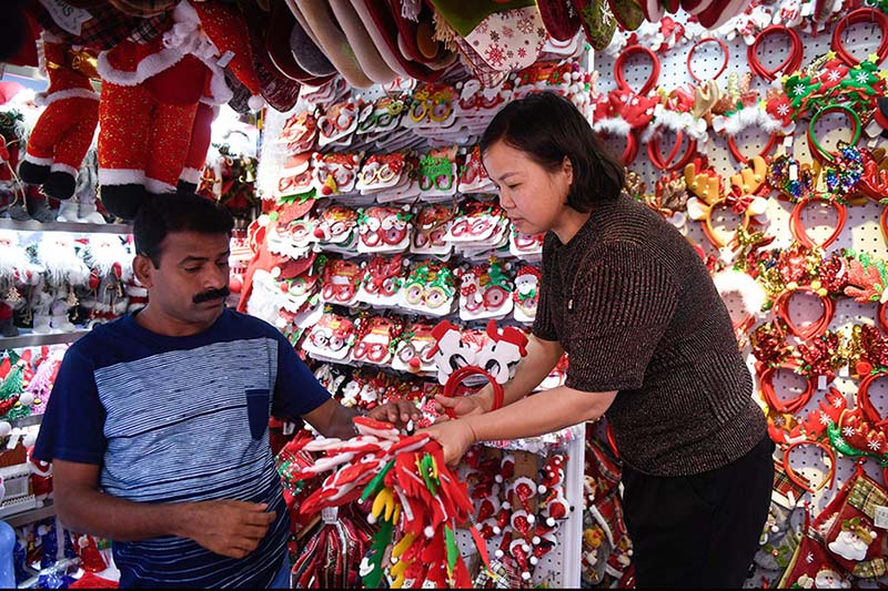 Un vendedor (derecha) muestra decoraciones navideñas en un mercado de la ciudad de Yiwu, provincia de Zhejiang, este de China. [Foto / Xinhua]