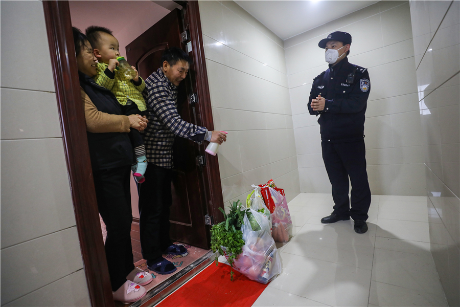 Yan observa cómo sus suegros esterilizan las bolsas de víveres que les ha comprado y entregado, 7 de febrero del 2020. [Foto: Yuan Zheng / China Daily]