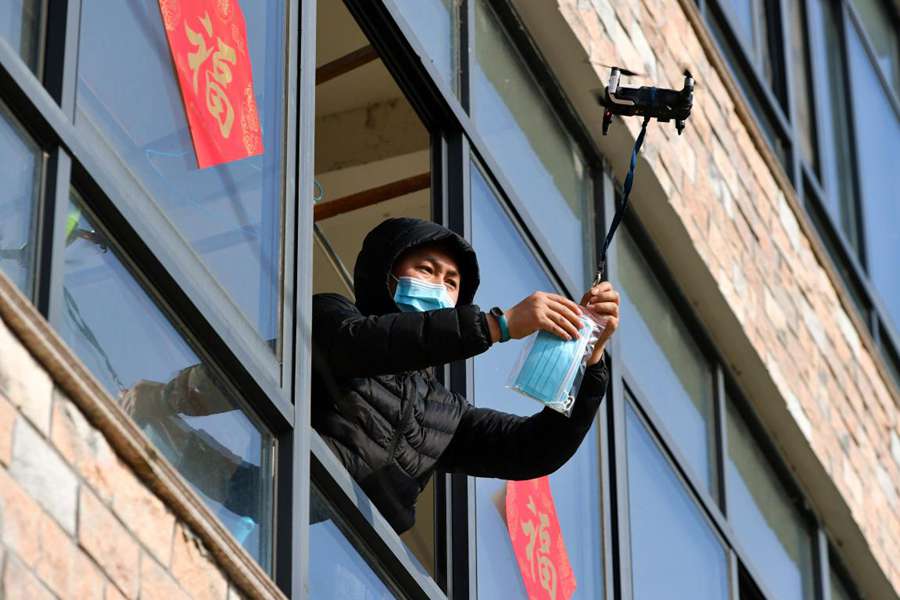 Un hombre en cuarentena domiciliaria en la aldea de Changping en Jiapu, condado Changxing de Huzhou, en la provincia de Zhejiang, recibe mascarillas faciales y un termómetro entregados con un dron el 9 de febrero de 2020. (Foto de Tan Yunfeng / Pueblo en Línea)