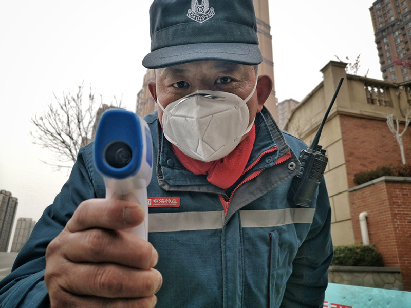Un portero comprueba la temperatura del fotógrafo, a la entrada de su comunidad, 4 de febrero del 2020. [Foto: Qian Han/ China Daily] 