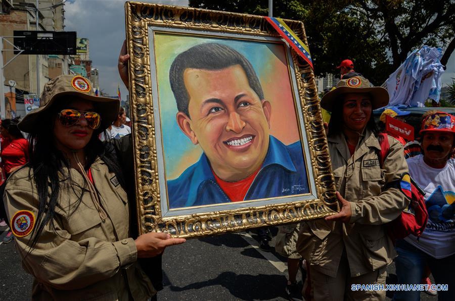 CARACAS, 8 marzo, 2020 (Xinhua) -- Dos integrantes de la Milicia Nacional Bolivariana sostienen un cuadro con la imagen del ex presidente venezolano Hugo Chávez, durante una manifestación por el Día Internacional de la Mujer en Caracas, Venezuela, el 8 de marzo de 2020. (Xinhua/Marcos Salgado)