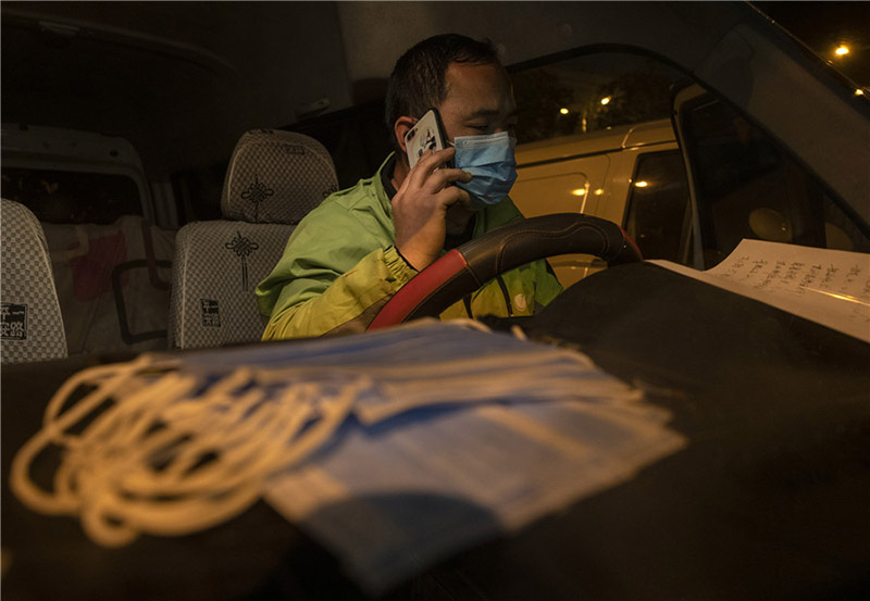 Ma Zengchen, repartidor de verduras, llama desde su camioneta a un colega para comprobar la información de entrega, Wuhan, provincia de Hubei, 7 de marzo del 2020. [Foto: Xinhua]
