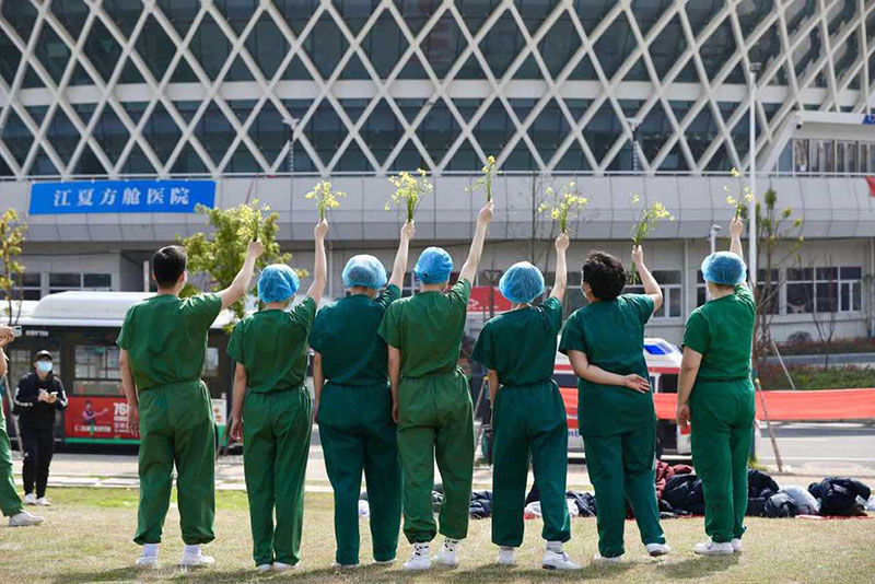 Los trabajadores de la salud posan para una foto de grupo después de que el último grupo de pacientes recuperados fue dado de alta del Hospital Jiangxia, un centro médico temporal  operado por profesionales de la medicina tradicional china en la provincia de Hubei, 10 de marzo del 2020. [Foto: Zhu Xingxin/ Chinadaily] 