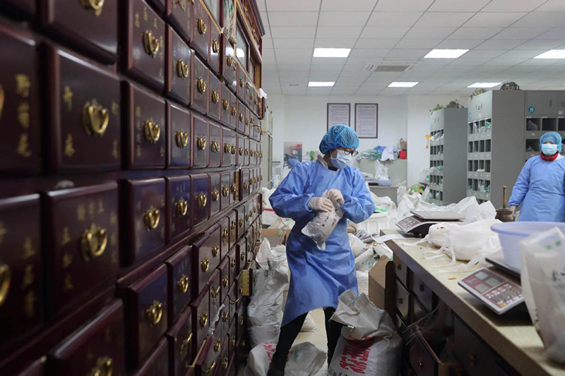 Una farmacéutica prepara una receta de medicina tradicional china en el Sexto Hospital de Wuhan, provincia de Hubei. [Foto por Wang Jing / China Daily]