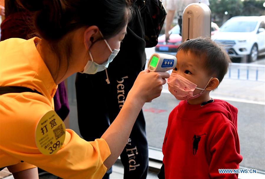Un miembro del personal comprueba la temperatura corporal de un niño en un restaurante en Zhengzhou, provincia de Henan. 