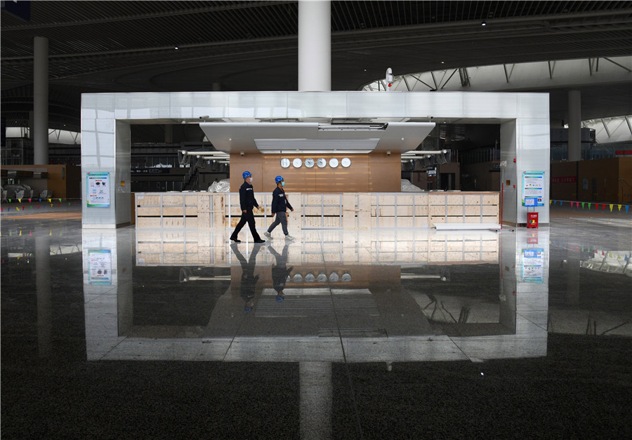 Dos técnicos pasan por una sala terminal en el Aeropuerto Internacional Jiaodong de Qingdao, provincia de Shandong, este de China, el 25 de marzo de 2020. [Foto / Xinhua]
