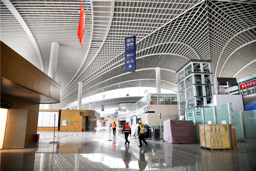 El personal de construcción pasa frente a una sala terminal del Aeropuerto Internacional Jiaodong de Qingdao, provincia de Shandong, este de China, el 25 de marzo de 2020. [Foto / Xinhua]