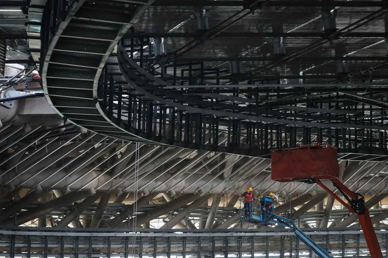 Los trabajadores suben a una plataforma elevadora en el sitio de construcción del Óvalo Nacional de Patinaje de Velocidad el 16 de abril [Foto de Kuang Linhua / China Daily]