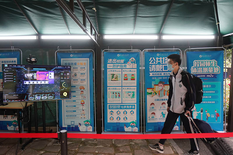 La foto tomada, el 6 de mayo de 2020, muestra a un estudiante de último año caminando a través de una estación de verificación de temperatura para ingresar en la Escuela Secundaria Experimental de Hubei Wuchang en Wuhan, capital de la provincia central china de Hubei. (Xinhua/Xiong Qi)