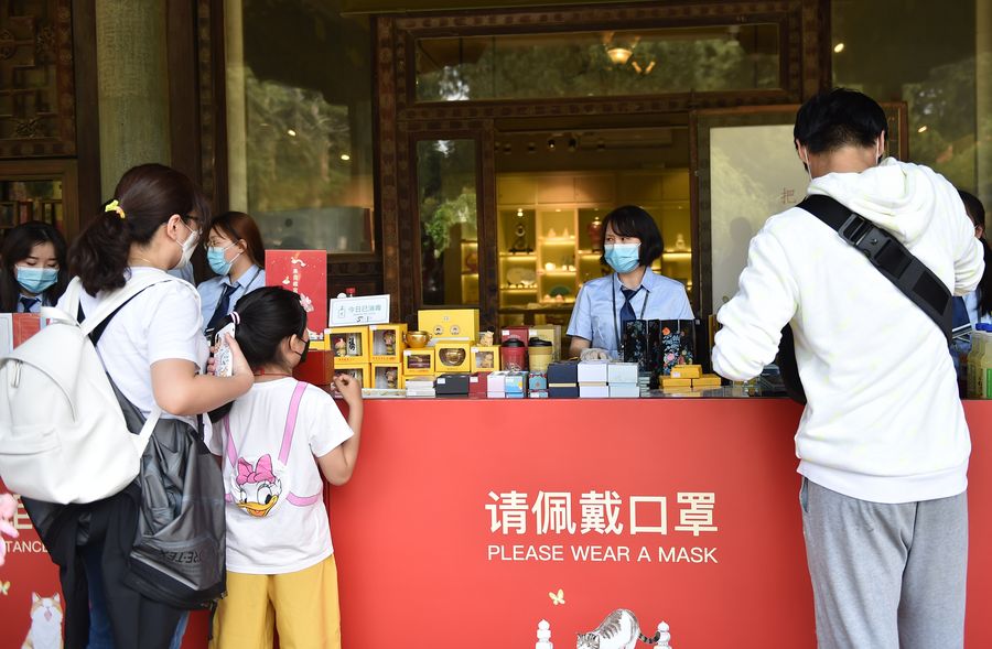 Visitantes compran recuerdos en una tienda que exhibe un letrero con información de prevención frente a COVID-19 en el Museo del Palacio en Beijing, capital de China, el 1 de mayo de 2020. (Xinhua/Chen Zhonghao)