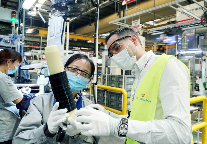 El 16 de abril, Mathieu (derecha), un técnico francés de Hutchinson Industrial Rubber Products (Suzhou) Co., Ltd., estudia la calidad de un producto con un técnico chino en el taller. (Hua Xuegen / vip.people.com.cn)