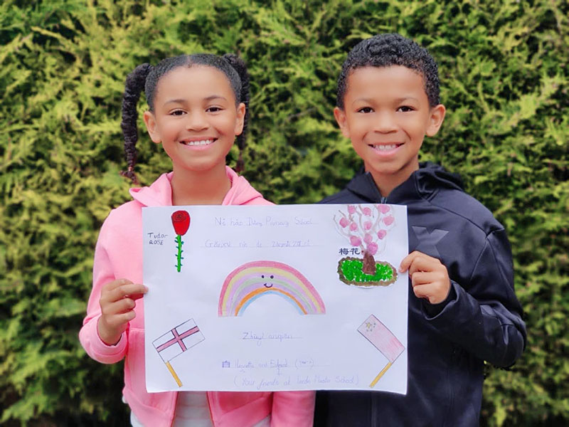 Dos niños del Reino Unido muestran un dibujo hecho para los alumnos de la Escuela Primaria Datong de Changsha, provincia Hunan. [Foto: proporcionada a China Daily] 