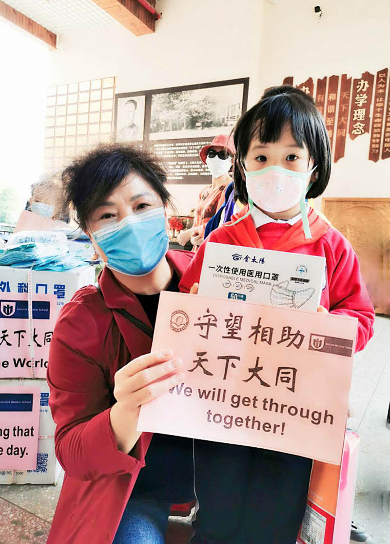Una alumna de la Escuela Primaria Datong y un miembro de su familia posan para una foto mientras empacan las máscaras que donaron para la Escuela Lincoln Minster de Reino Unido. [Foto: proporcionada a China Daily] 