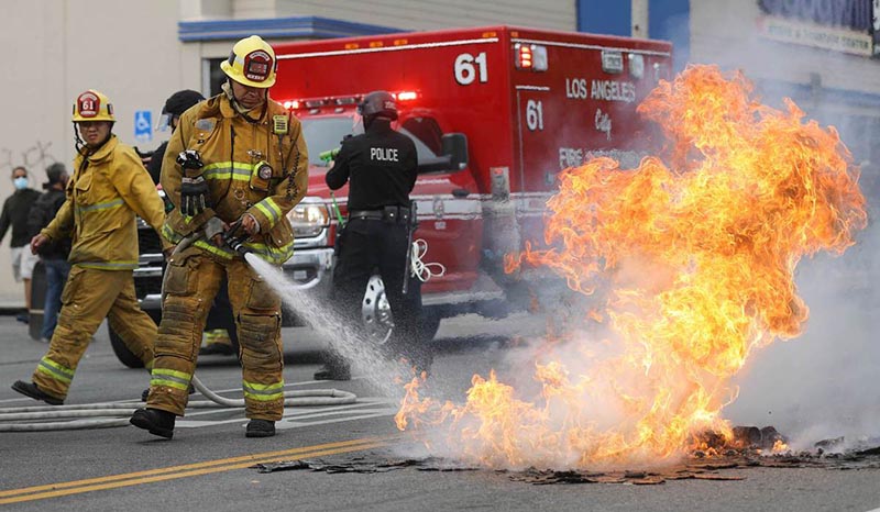 Un bombero extingue un pequeño incendio callejero durante las manifestaciones ocurridas tras la muerte de George Floyd, Los Angeles, California, 30 de mayo del 2020. [Foto: agencias]