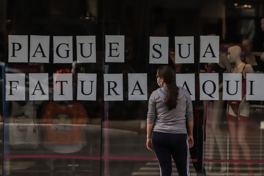 Una mujer porta una mascarilla frente a una tienda cerrada que dice "Pague su factura aquí" durante el brote de la enfermedad causada por el nuevo coronavirus (COVID-19) en Sao Paulo, Brasil, el 8 de junio de 2020. (Xinhua/Rahel Patrasso)