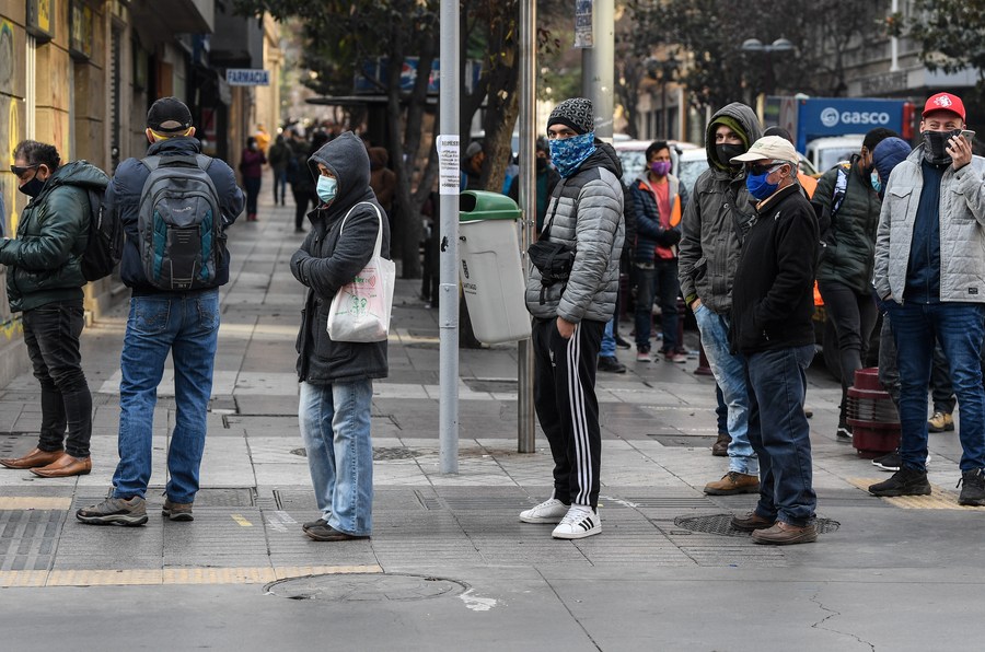 Personas portan mascarillas mientras se forman en fila frente al edificio de la Administradora de Fondos de Cesantía de Chile, en Santiago, capital de Chile, el 11 de junio de 2020. (Xinhua/Jorge Villegas)