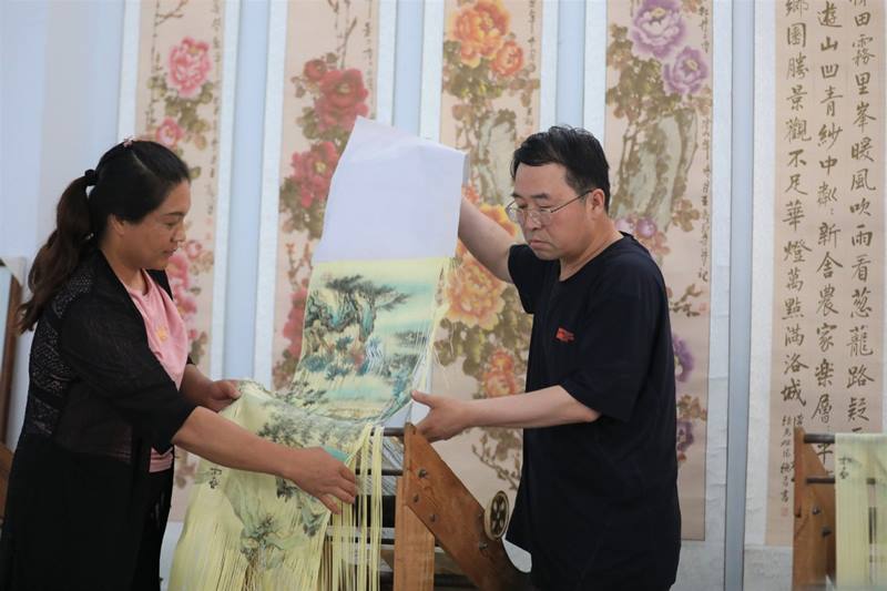 Wei recorta una pintura de tinta con la ayuda de su esposa Ma Wenhua, condado de Zhuanglang, ciudad de Pingliang, provincia de Gansu, 8 de julio del 2020. [Foto: Xinhua]