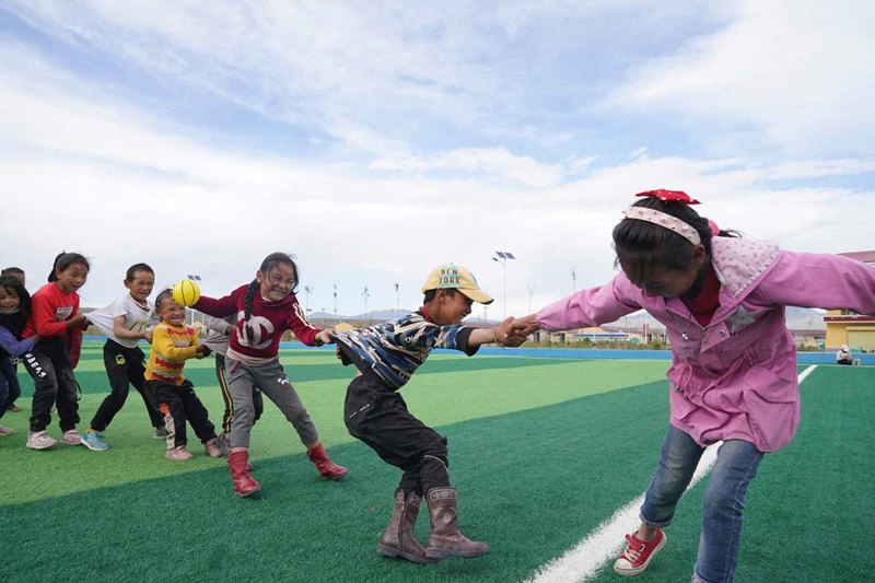Niños juegan en un campo de fútbol en la Aldea Cultural Amdo, un proyecto de reasentamiento para familias pobres, en el condado Xinghai, provincia de Qinghai. [Foto de Feng Yongbin / China Daily]
