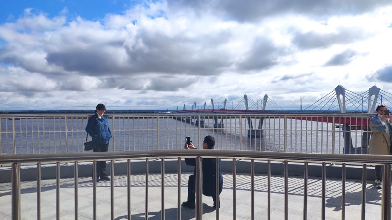 Los visitantes se hacen fotos en la torre turística construida a un lado del primer puente que conecta China y Rusia sobre el río Heilongjiang. [Foto de Zhang Wenfang / chinadaily.com.cn]