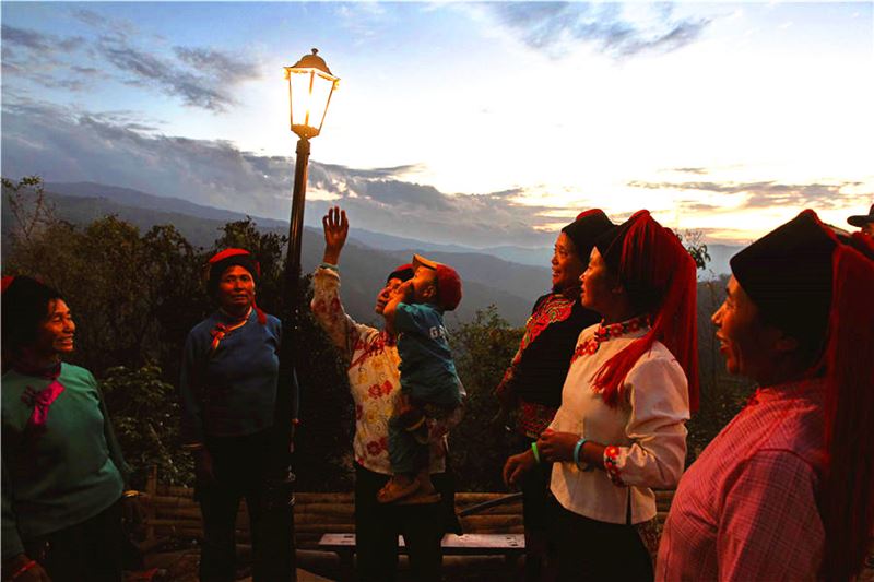 Los aldeanos charlan bajo una lámpara fotovoltaica en la aldea Shaguo en la prefectura autónoma Hani y Yi de Honghe en Yunnan, el 11 de diciembre de 2013. La Fundación de Protección Ambiental de China instaló sistemas de generación de energía fotovoltaica para ayudarlos. [Foto de Deng Jia / para China Daily]