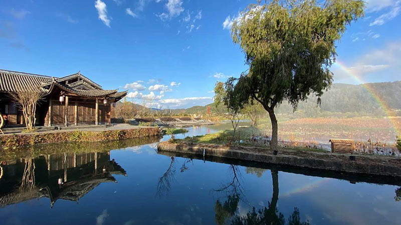 El reflejo de un árbol, un arco iris y un edificio se funde en el resplandeciente río Xianhe, de la ciudad antigua de Heshun, provincia de Yunnan, 7 de diciembre del 2020. (Foto: Pueblo en Línea/ Meng Bin)