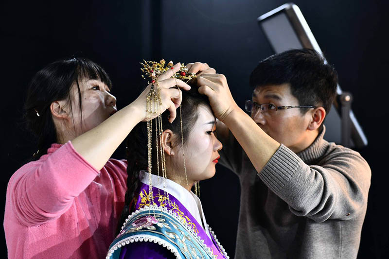 Hu Chunqing y su esposa Meng Xiaoxia ayudan a un estudiante. [Foto: Xinhua]