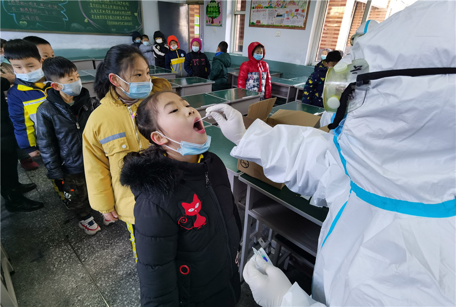 Un trabajador médico toma una muestra de garganta de una estudiante en una escuela primaria en Xingtai, provincia de Hebei, el 6 de enero de 2021. [Foto de Huang Tao / Para China Daily]