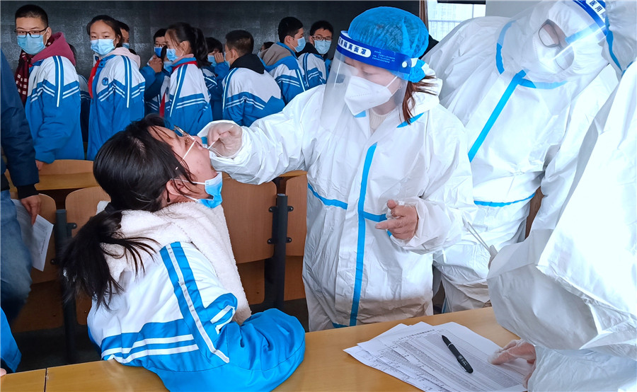 Un trabajador médico toma una muestra de garganta de una estudiante de una escuela secundaria en Xingtai, provincia de Hebei, el 6 de enero de 2021. [Foto de Huang Tao / Para China Daily]