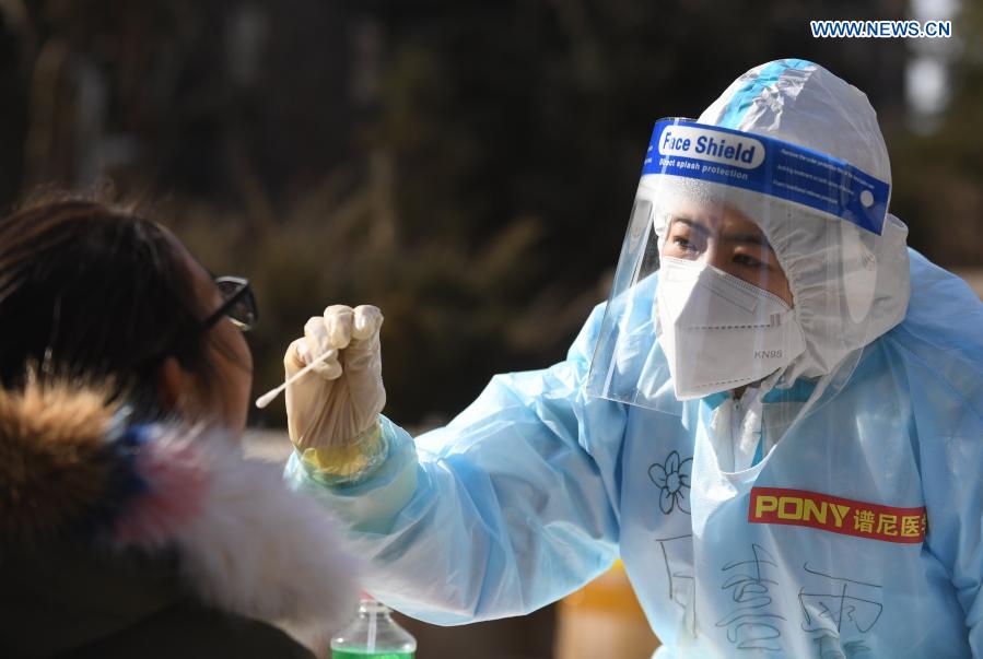 Un trabajador de la salud recoge muestras de hisopo de un residente en un sitio de pruebas en una comunidad del distrito Yuhua, Shijiazhuang, capital de Hebei, 10 de enero del 2021. La segunda ronda de las pruebas de ácido nucleico ha comenzado en algunas comunidades de Shijiazhuang. [Foto: Xinhua]