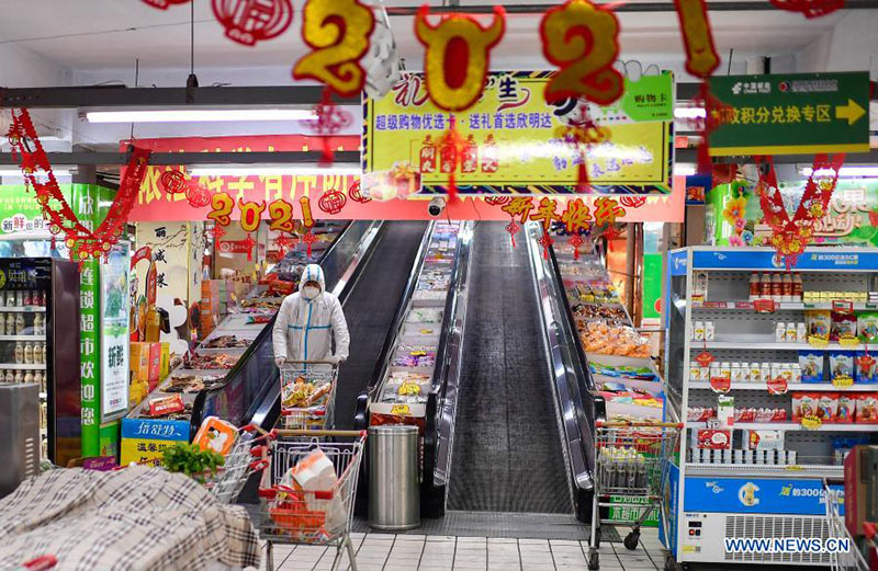 Un voluntario compra artículos de primera necesidad de acuerdo con los pedidos en línea de los residentes en cuarentena en un supermercado en el distrito Dongchang de Tonghua, provincia de Jilin, noreste de China, el 24 de enero de 2021. 