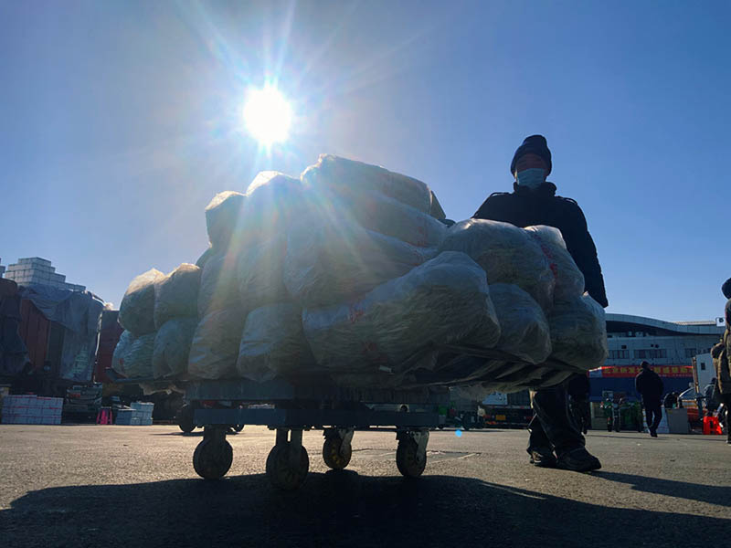 Un vendedor carga su carro con verduras frescas en el mercado mayorista de alimentos Xinfadi en Beijing, el 1 de febrero de 2021 (Pueblo en Línea / Kou Jie).