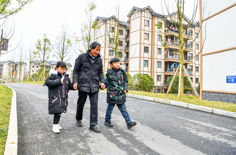Li Changde camina con los niños después de recogerlos en la escuela de una comunidad de nueva construcción que forma parte del programa de alivio a la pobreza en la antigua ciudad de Shexiang, Dafang, Guizhou, 23 de diciembre del 2020.