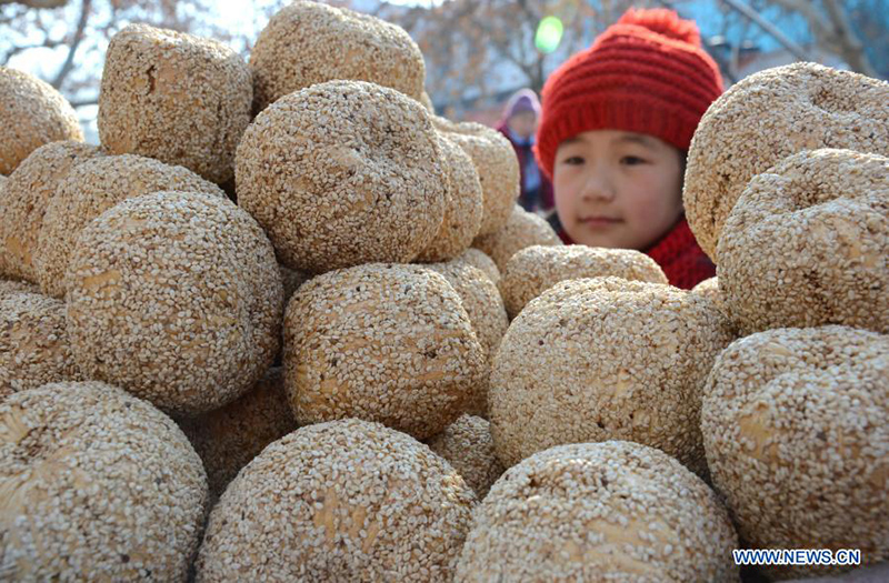 Un niño compra "melón de azúcar", un aperitivo de Año Nuevo Chino hecho de azúcar de malta, arroz glutinoso y sésamo, en el condado Yiyuan de la provincia de Shandong, en el este de China, el 10 de febrero de 2015. [Foto / Xinhua]