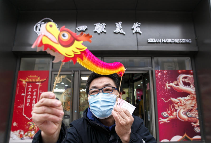 Un residente en la capital china recibe un dragón en la barbería-peluquería Silian, ubicada en la atractiva calle de Wangfujing, hoy tuvo que “madrugar” para atender a la mayor cantidad de clientes diarios del año, Beijing, 14 de marzo del 2021. [Foto: Jiang Dong/ China Daily]